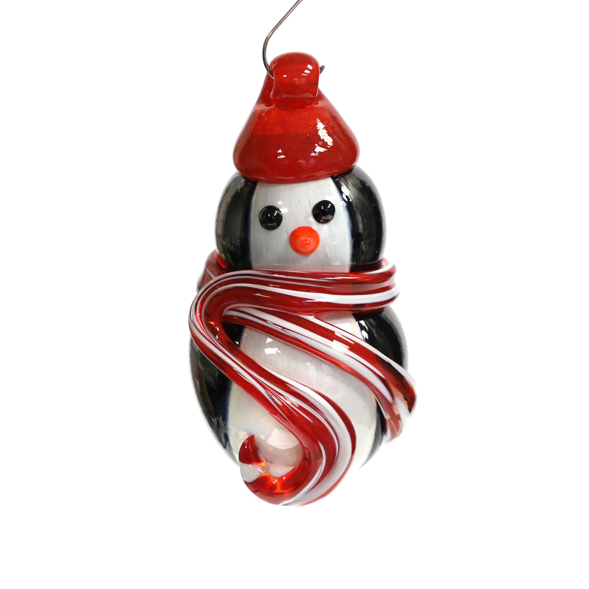 Glass holiday ornament in the shape of a penguin. The penguin is wearing a red hat and red and white scarf.
