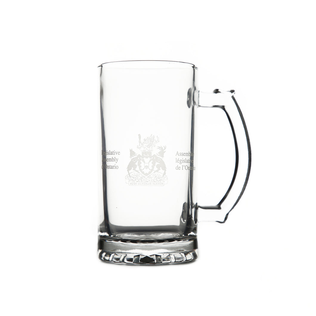 Clear glass beer stein with Legislative Assembly coat of arms etched on front centre