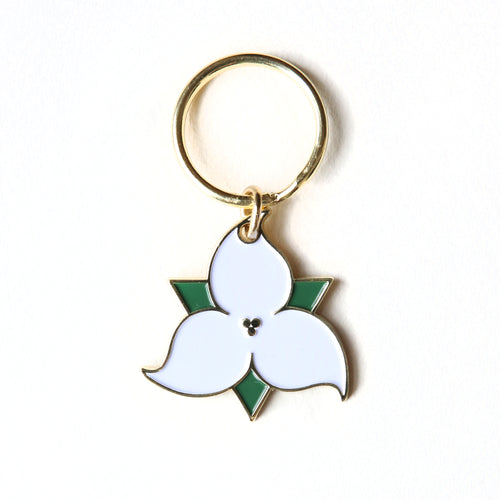 Key ring of the white trillium flower with green leaves.